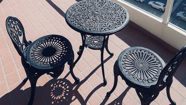 A balcony with a table and chairs, a railing, and a view of buildings and trees. - Modern Apartment in Sydney CBD Heart (Sydney)