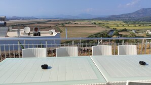 A terrace with white wicker furniture and a view of a rural landscape with fields and mountains. - Villa Beyaz İnci Dalaman-Villa White Pearl Dalaman (Dalaman)