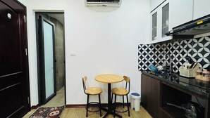 A compact kitchen with a round table and two chairs, a tiled backsplash, and a built-in oven. - Ly Home Tay Ho Ha Noi  (Hanoi)
