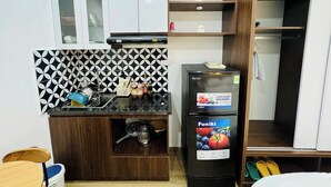 A compact kitchen with a black and white patterned backsplash, a black refrigerator, and wooden cabinets. - Ly Home Tay Ho Ha Noi  (Hanoi)