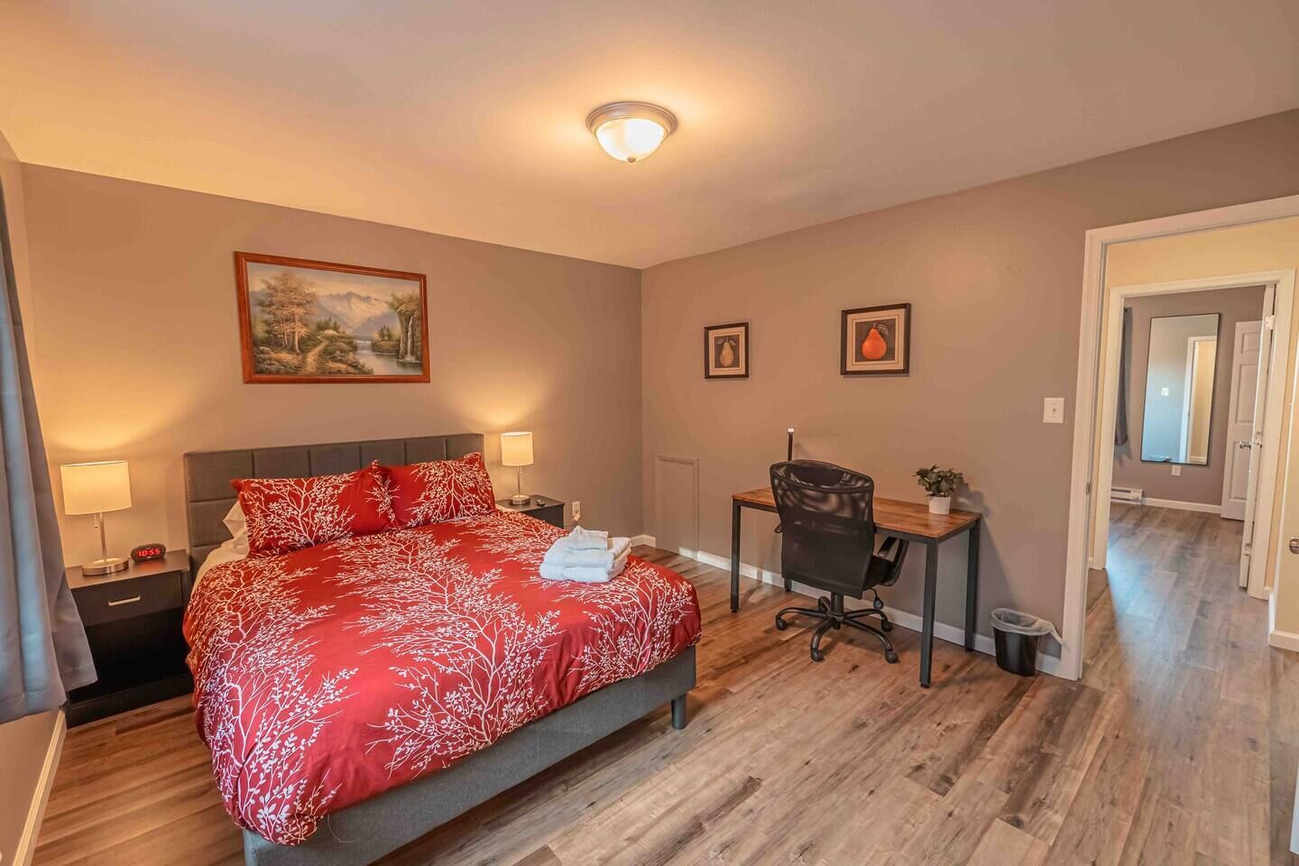 Un dormitorio con cama, escritorio, silla y un cuadro en la pared.