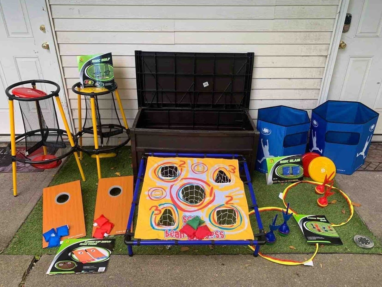 A garage with a black storage box, a trampoline, and a children's play area with a net and hoops.