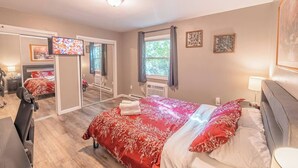 Un dormitorio con cama, escritorio, silla, televisor y ventana con cortinas.