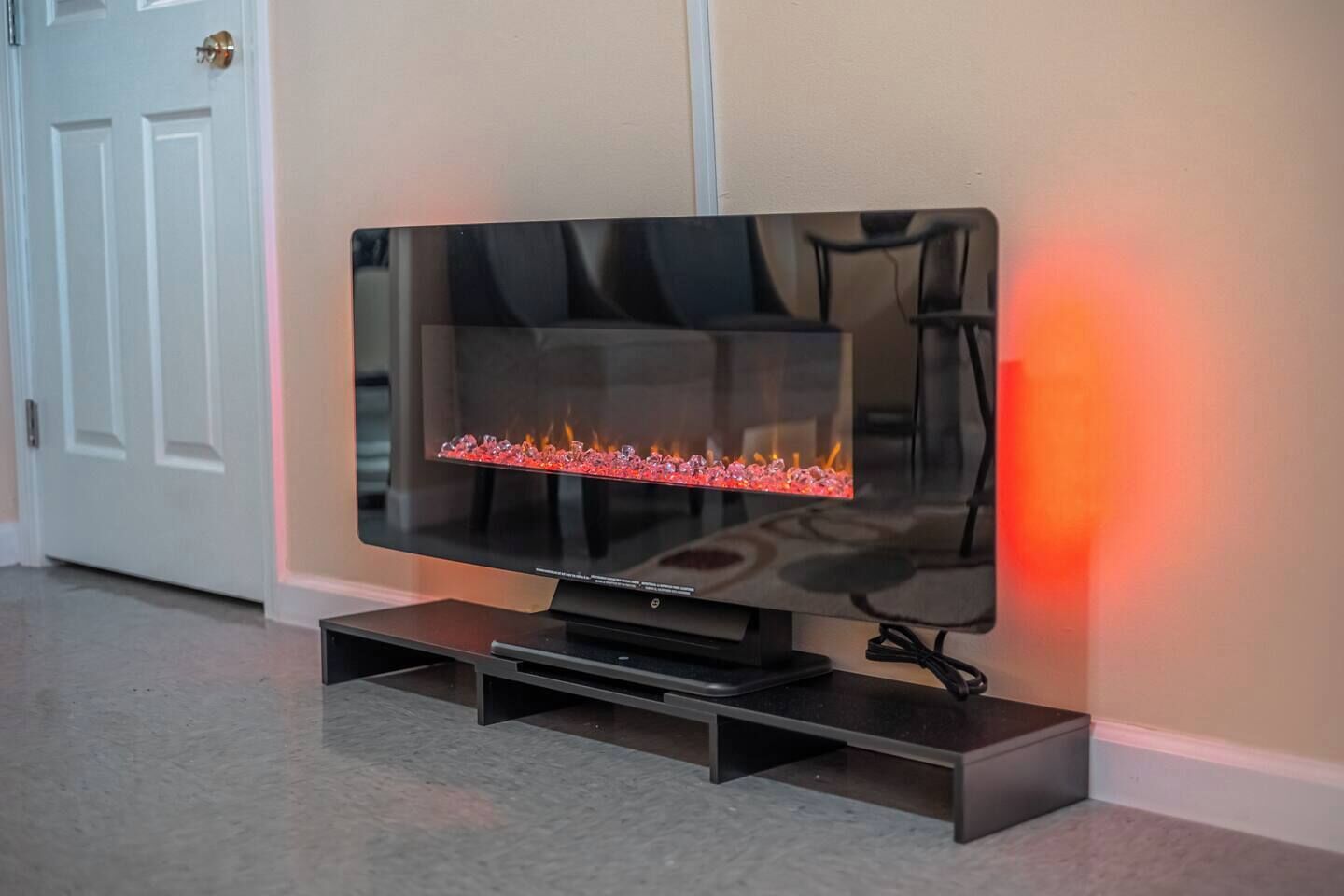 Een flatscreen televisie met ingebouwde open haard, geplaatst op een bijzettafeltje in een hal.