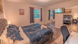 Un dormitorio con cama, escritorio, silla, ventana y espejo.