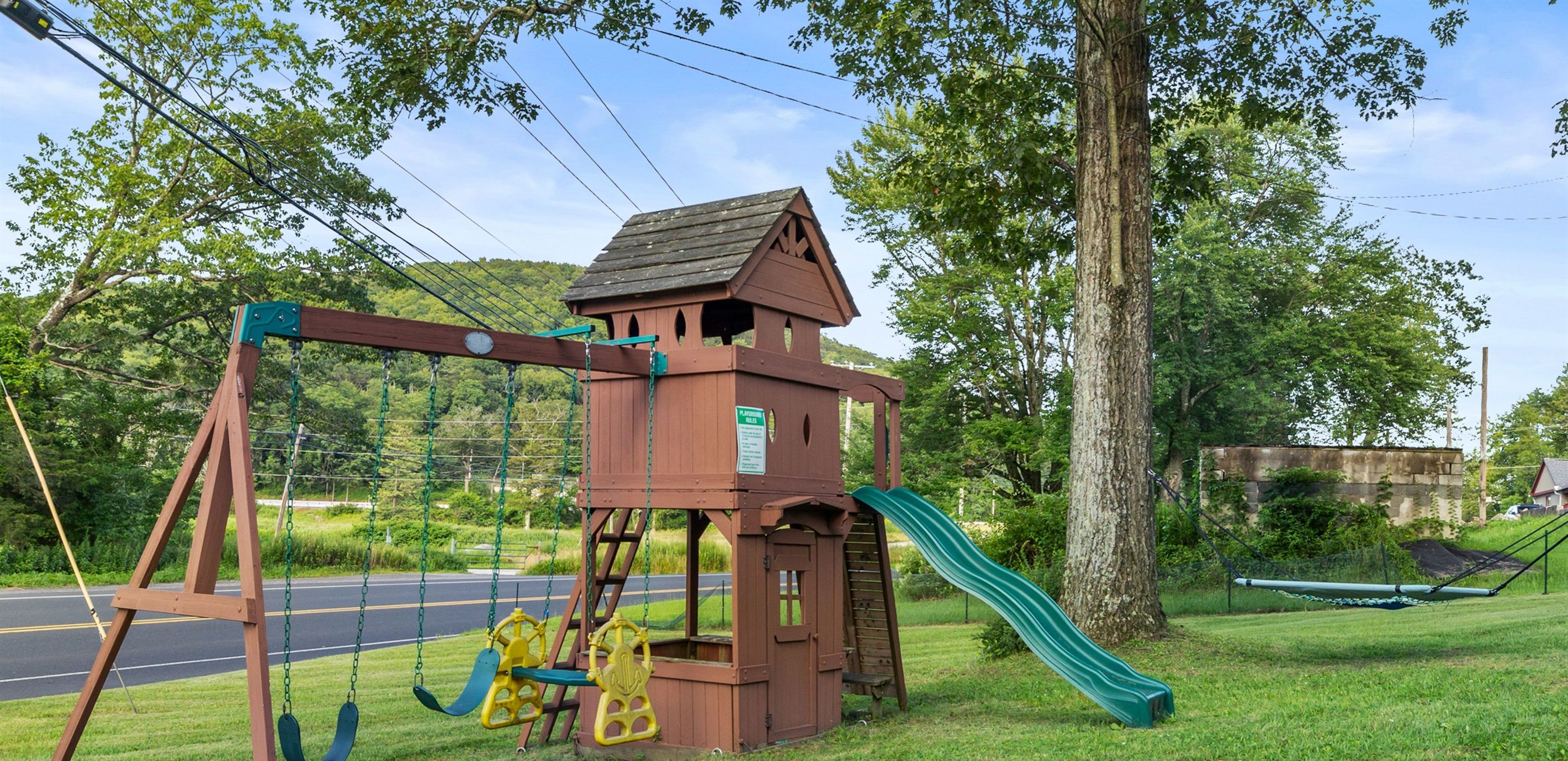 A playground with swings, a slide, a climbing wall, a sand pit, and a bungee hammock.