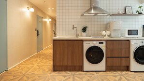 Une cuisine moderne avec des meubles en bois, un lave-linge encastré, un four à micro-ondes et un évier.
