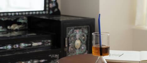 A glass of amber liquid on a wooden table with a book beside it.