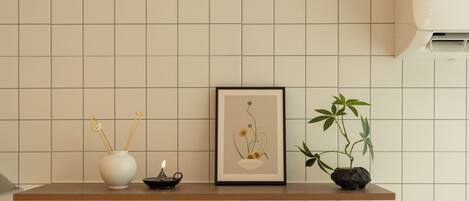 A shelf with a white vase, a framed picture, a small candle, and a potted plant.