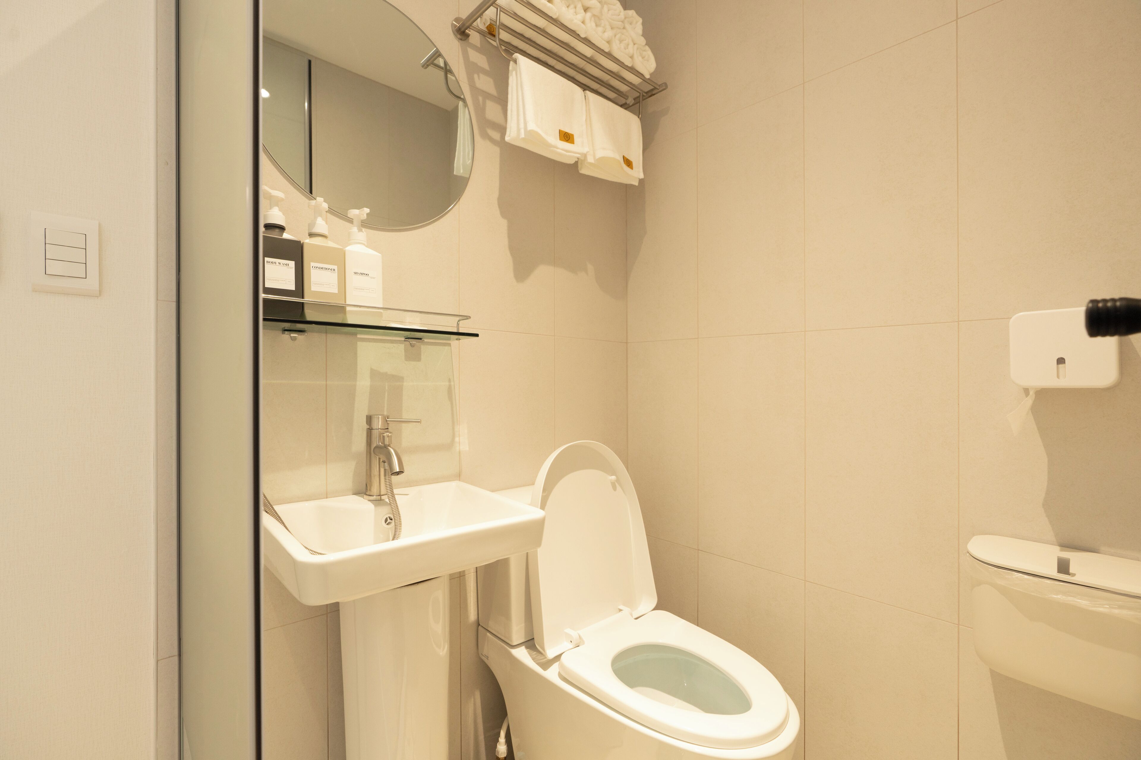 Een moderne badkamer met toilet, wastafel en spiegel.