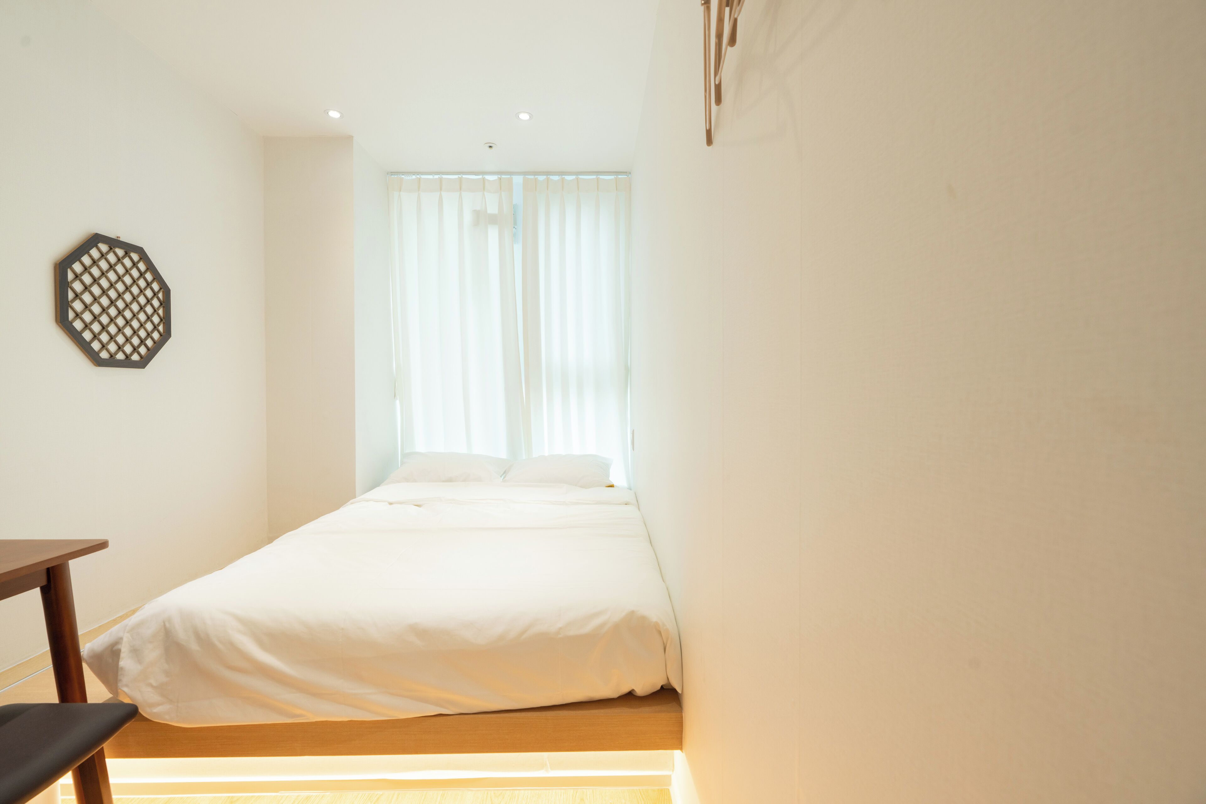 Ein schlicht eingerichtetes Schlafzimmer mit einem Einzelbett, einem Nachttisch aus Holz und einer Wanddekoration.
