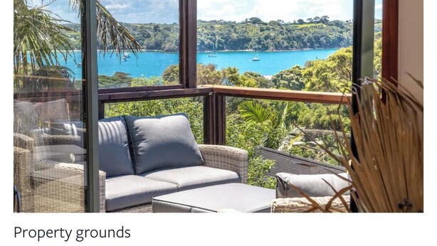 A property ground with a glass-enclosed balcony overlooking a scenic bay with boats and lush greenery. - Tawa Street, Oneroa - Blue Sky Retreat - Spa pool (waiheke island)