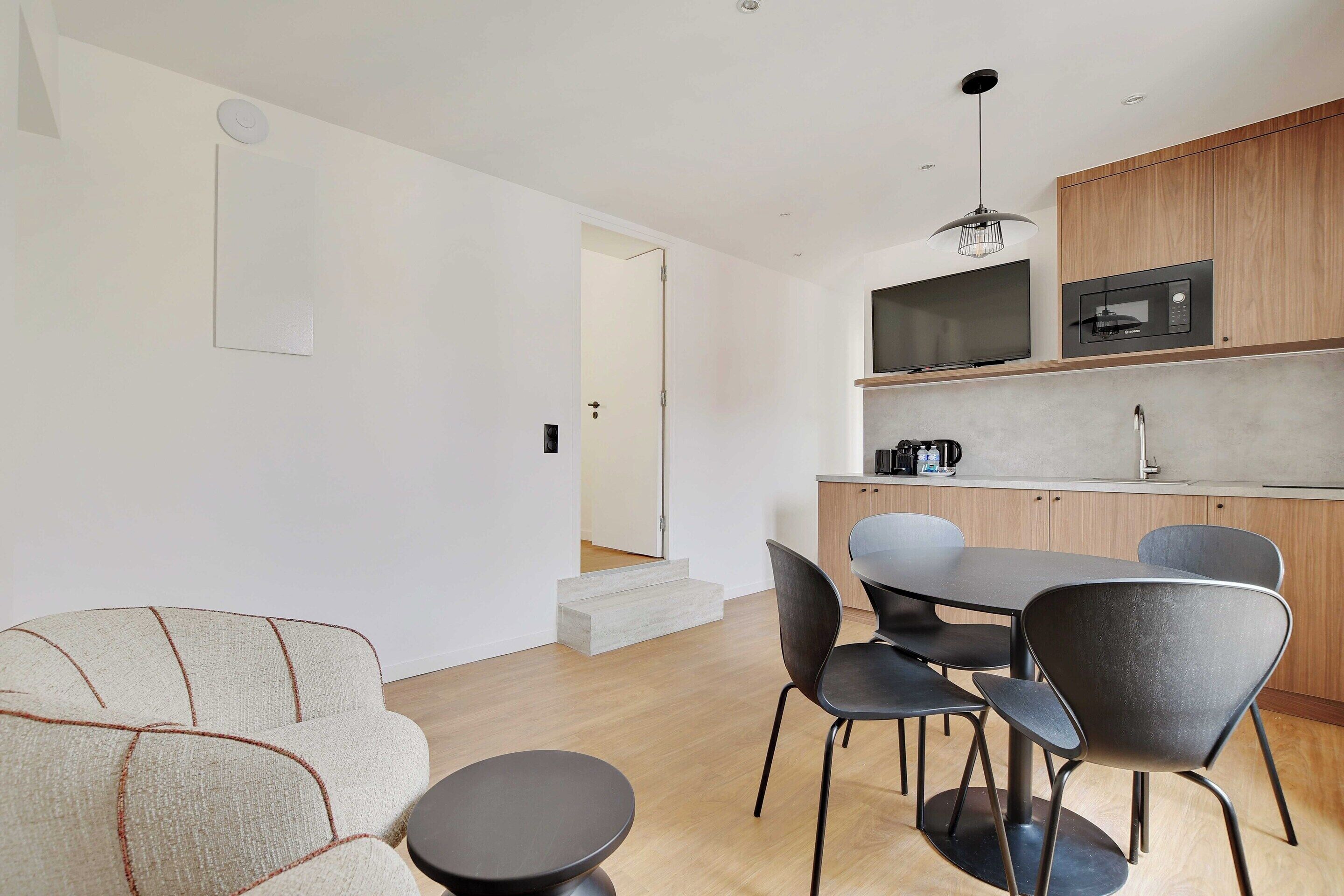 A modern kitchen with a microwave, a dining area with a table and chairs, and a staircase leading to another room.
