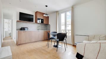 Una cocina moderna con armarios de madera, un televisor integrado y una zona de comedor con una mesa redonda y sillas.