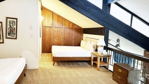 A bedroom with a sloped ceiling, wooden wardrobe, a bed with pillows, a bedside table with a lamp, and a dresser. - Great Rates and Month Stays Available! Slope Views, Near Mountain/Base/Eat, Spacious with Loft (Steamboat Springs)