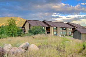 A building with a flat roof and multiple windows, surrounded by grass and rocks.