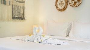 Een hotelkamer met een net opgemaakt bed, een wand met decoratieve wandversieringen, en een nachtkastje met een lamp.