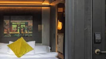 Une chambre d’hôtel moderne, avec un lit, un tableau au mur et une porte dotée d’une poignée.