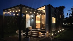 Et moderne hus med en overdækket terrasse, et synligt køkken og en velbelyst indgang.