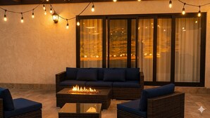 An outdoor seating area with a fire feature, wicker furniture, and string lights. - Baja Toscana Rancho Olivares (Valle de Guadalupe)
