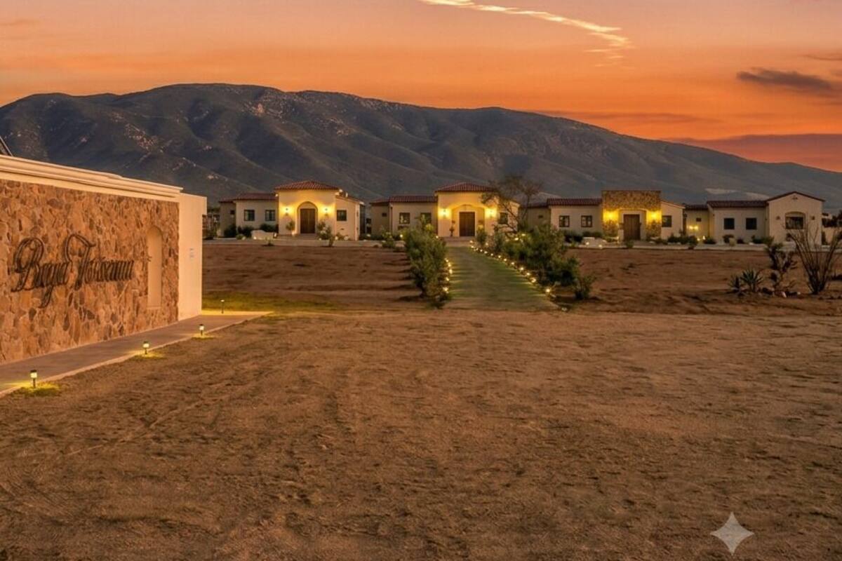 A desert landscape with a row of houses at sunset.