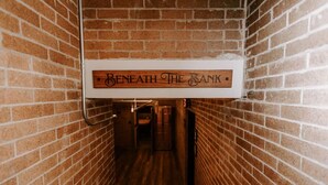 A narrow brick corridor with a sign reading "Beneath The Bank." - The Bonnie & Clyde Room @ The Bank (East Aurora)
