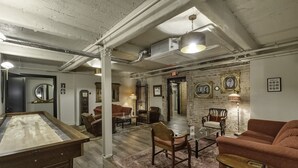 A room with a pool table, leather chairs, a coffee table, and a sofa. There are framed pictures on the wall and a clock. - The Slick Willie Sutton Room @ The Bank (East Aurora)