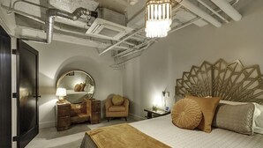 Een slaapkamer met een bed, een dressoir, een spiegel, een stoel en een nachtkastje.