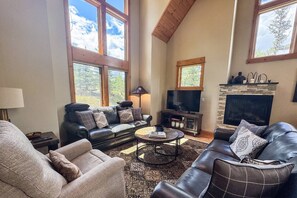 A living room with a fireplace, leather sofas, a coffee table, and large windows. - Must See! Gorgeous Updated Home, Fireplace, Vaulted Ceilings, Hot Tub, Deck, Garage, Great Location (Mountain Village)