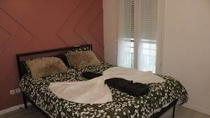 A bed with a patterned bedspread, a pillow, and a blanket. - Beautiful apartment in Meaux, 15 minutes from Disneyland (Meaux)