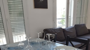 A dining table set with plates, cutlery, and wine glasses, with a view of a sofa and blinds in the background. - Beautiful apartment in Meaux, 15 minutes from Disneyland (Meaux)
