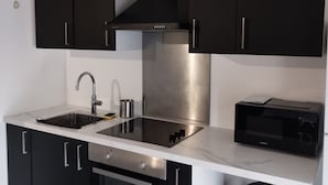 A modern kitchen with black cabinets, stainless steel appliances, a double sink, and a trash bin. - Beautiful apartment in Meaux, 15 minutes from Disneyland (Meaux)