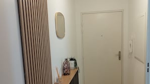 A hallway with a wooden floor, a white door, a mirror, and a pendant light. - Beautiful apartment in Meaux, 15 minutes from Disneyland (Meaux)