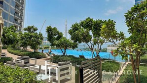 A pool area with lounge chairs and a view of a tall building in the background. - LUX 52 42 Deluxe Marina View Suite 3 (Dubai)
