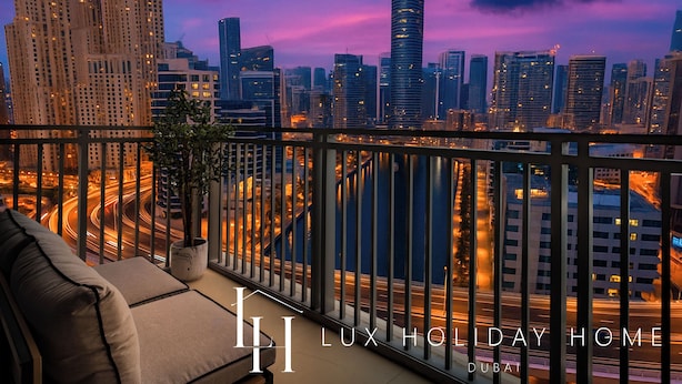 A balcony with a view of a cityscape at dusk, featuring high-rise buildings and a river. - LUX 52 42 Deluxe Marina View Suite 3 (Dubai)