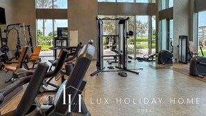 A spacious gym with various exercise equipment, large windows, and a view of the outdoors. - LUX 52 42 Deluxe Marina View Suite 3 (Dubai)