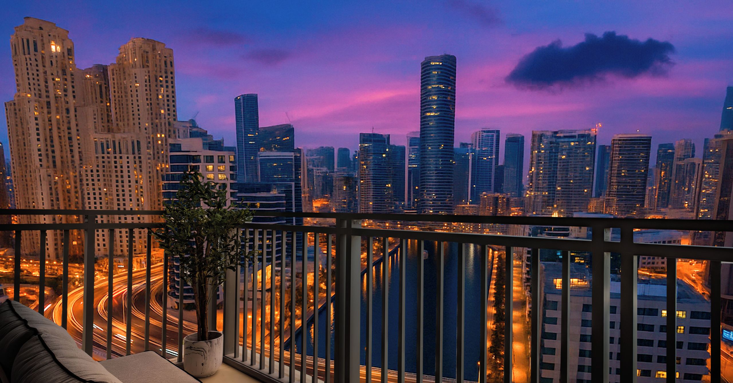A balcony with a view of a cityscape at dusk, featuring high-rise buildings and a river.
