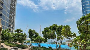 A pool area with lounge chairs and a view of a tall building in the background. - LUX 52 42 Deluxe Marina View Suite 3 (Dubai)