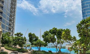 Ein Poolbereich mit Liegestühlen und Blick auf ein hohes Gebäude im Hintergrund.