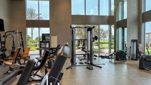 A spacious gym with various exercise equipment, large windows, and a view of the outdoors. - LUX 52 42 Deluxe Marina View Suite 3 (Dubai)