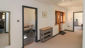 Un couloir avec un miroir, un banc et une porte donnant sur une pièce.