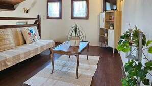 A cozy attic room with wooden beams, a sofa, a table, and a potted plant.