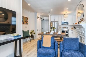 A modern kitchen with white cabinets, stainless steel appliances, and a dining area with blue chairs and a wooden table.