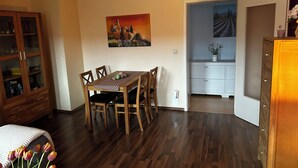 A dining area with a wooden table and chairs, a cabinet with glass doors, and a painting on the wall. - Olivia Vacation Rental in Hönow (Hoppegarten)
