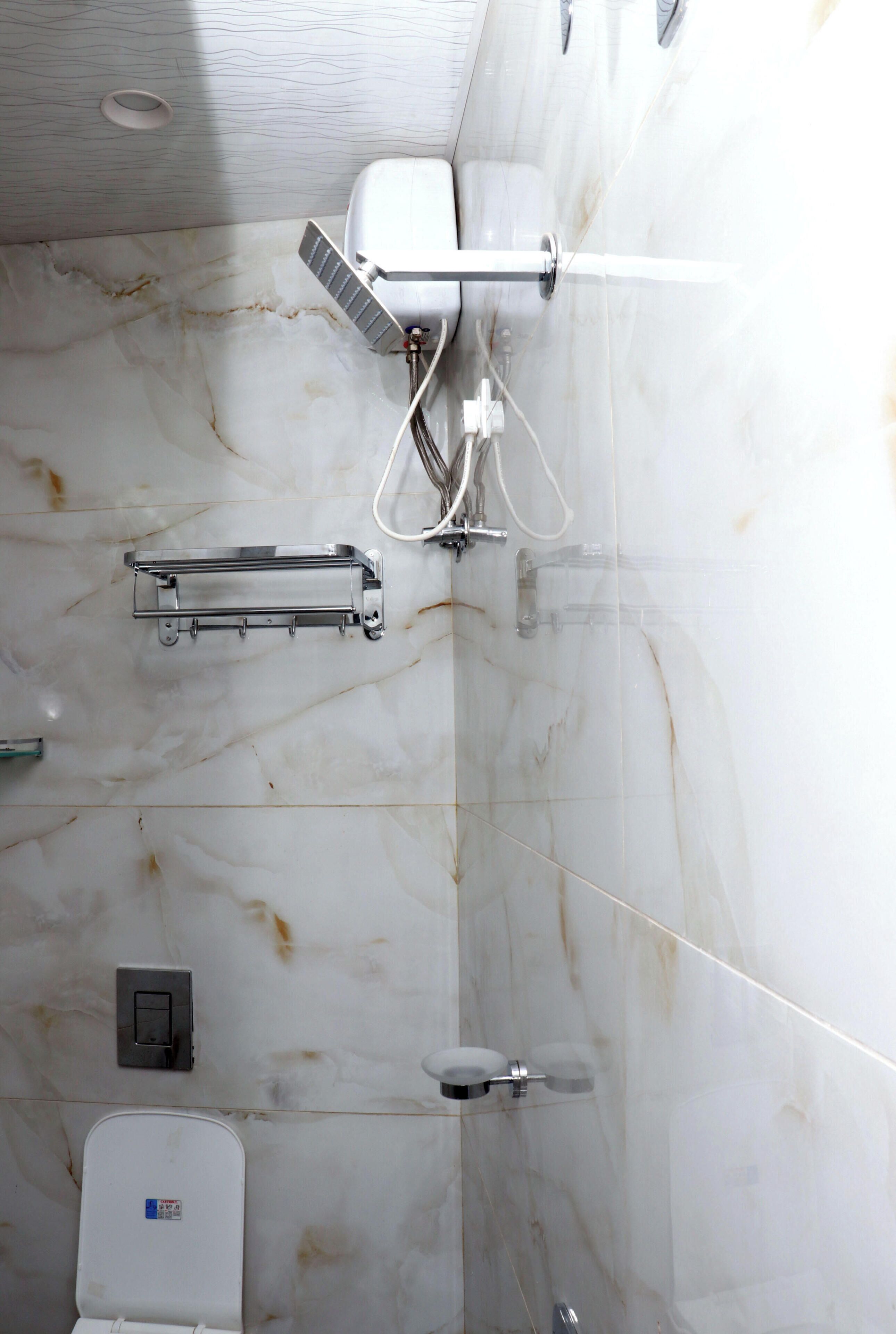 Une salle de bain avec un sol en marbre, des toilettes, une douche et un porte-serviettes.