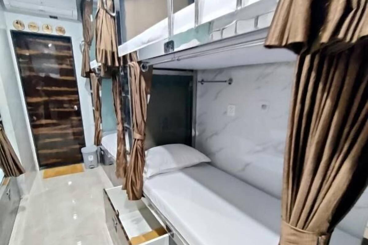 Habitación con literas, suelo de mármol, una mesita de noche pequeña y cortinas.