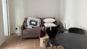 A modern living room with a brown sofa, a round table, and a black chair. - Modern Apartment - 1br-4p - Montreuil (Montreuil)