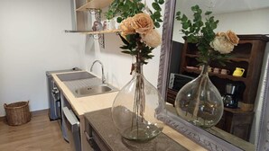 A kitchen with a sink, a mirror, a vase with flowers, and a shelf with decorative items. - Au Mont Chablis (Champagnole)