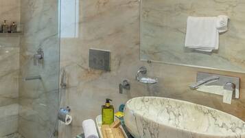 A bathroom with a glass-enclosed shower, a white toilet, a marble sink, and wooden cabinets.