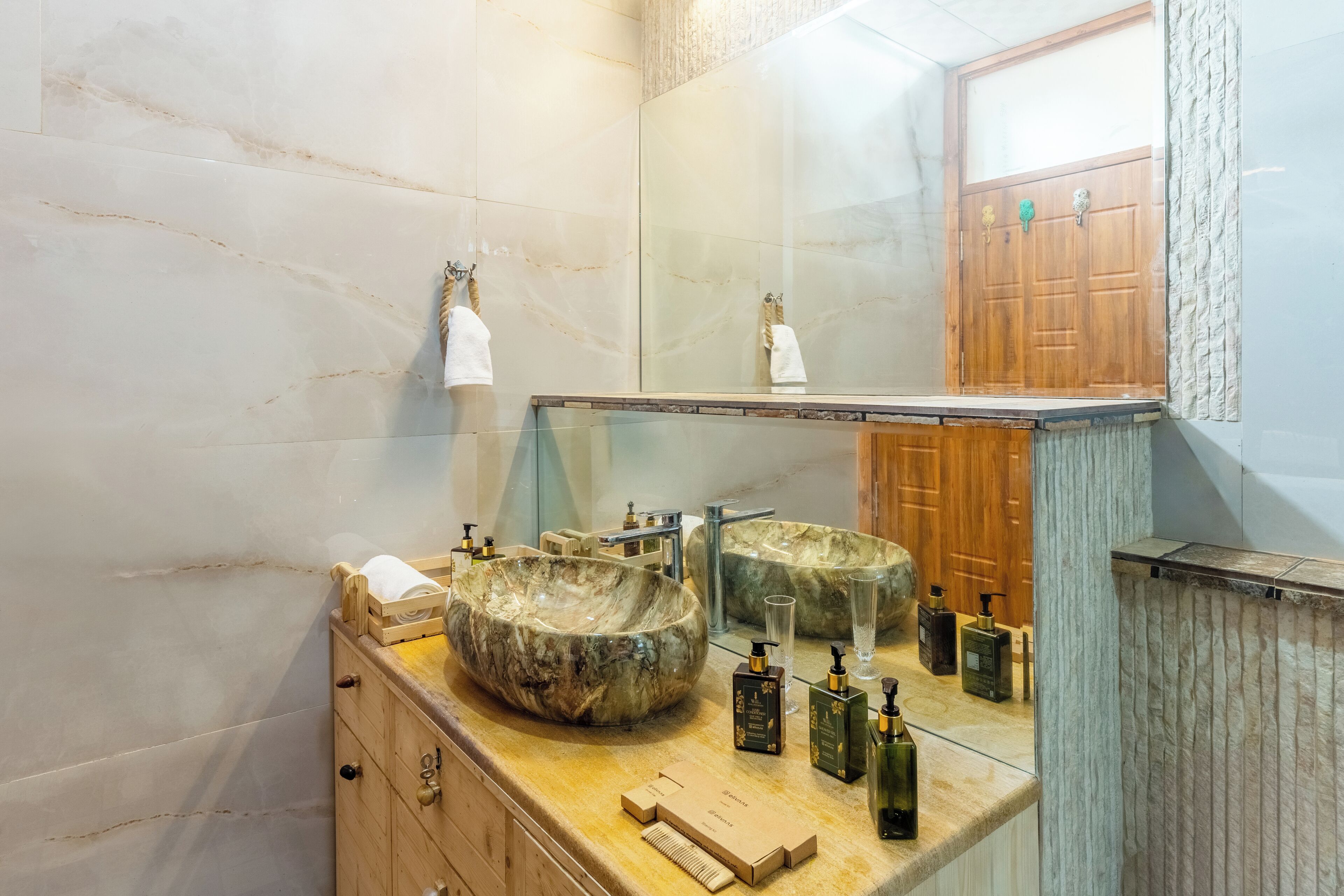 A bathroom with two large marble sinks, a mirror, and wooden cabinets.